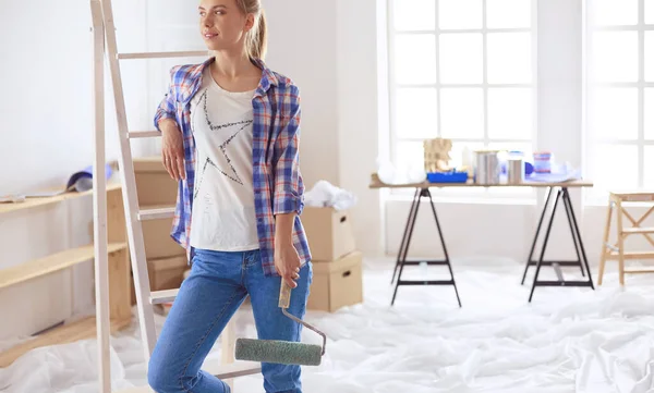 Smiling beautiful woman painting interior wall of home