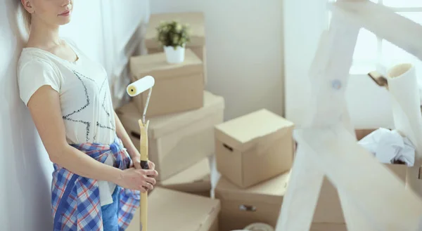 Glad leende kvinna målning interiör vägg i nytt hus — Stockfoto