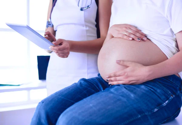 Doctora joven examinando a una mujer embarazada en la clínica. — Foto de Stock