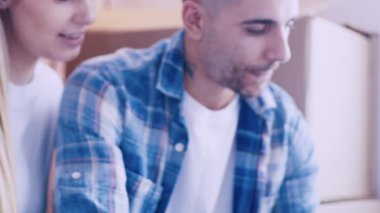 Genç ve çekici bir çift yerde oturan ve yeni evlerinin tabletine bakıp tasarımı düşünüyorlar. Kapalı