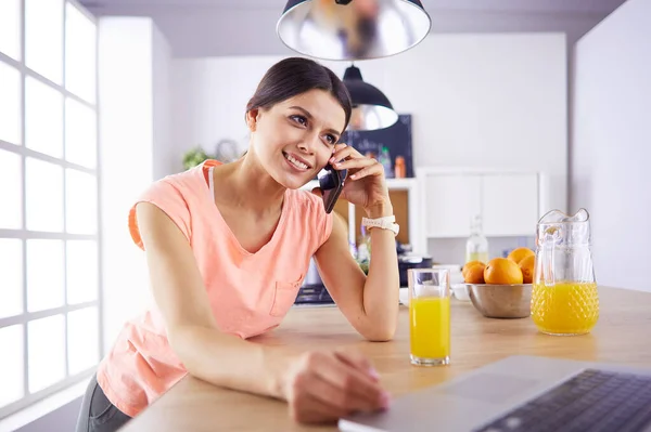 Молодая женщина на кухне с ноутбуком компьютер ищет рецепты, улыбаясь. Концепция пищевого блогера — стоковое фото