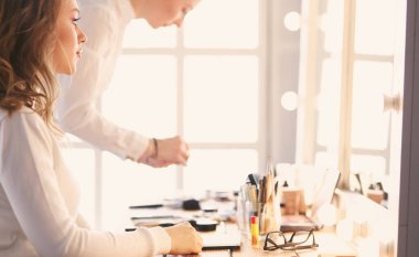 Makyöz, genç bir kadının profesyonel makyajını yapıyor.