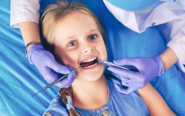 Küçük kız dişçi ofisinde oturuyor..