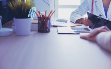 Bir doktor konuşuyor ve bir hastayı muayene ediyor.