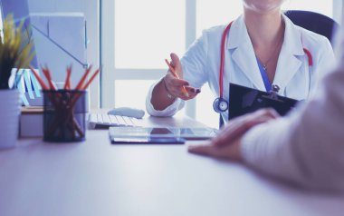 Bir doktor konuşuyor ve bir hastayı muayene ediyor.