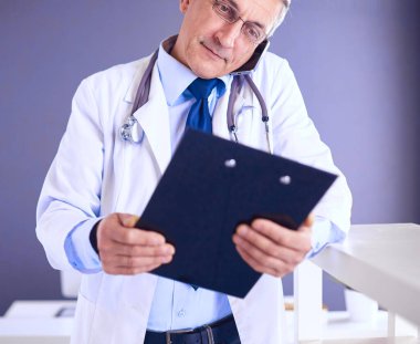 Erkek doktor hastanedeki panoya notlar yazıyor.