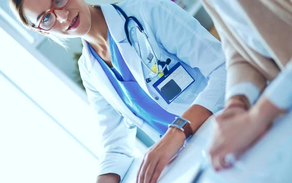 Dokter en geduldig stel bespreken iets, zitten op het bureau. — Stockfoto