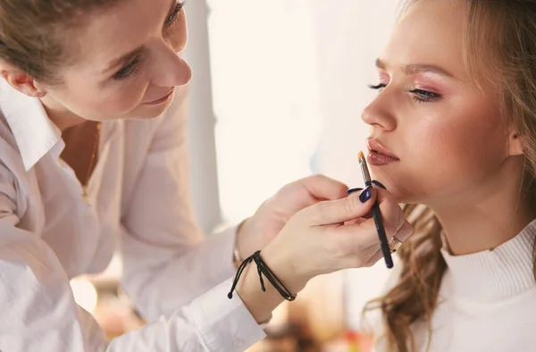 Tvoří umělec dělá profesionální make-up mladé ženy — Stock fotografie