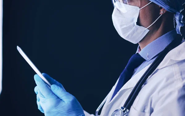 Doctor in hospital sitting at desk looking at x-rays on tablet against white background with x-rays — Stock Photo, Image