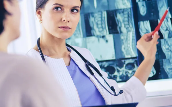 Il medico di medicina femminile spiega alla diagnosi del paziente che punta con la penna all'immagine dei raggi X. Paziente che ascolta attentamente le raccomandazioni del medico . — Foto Stock