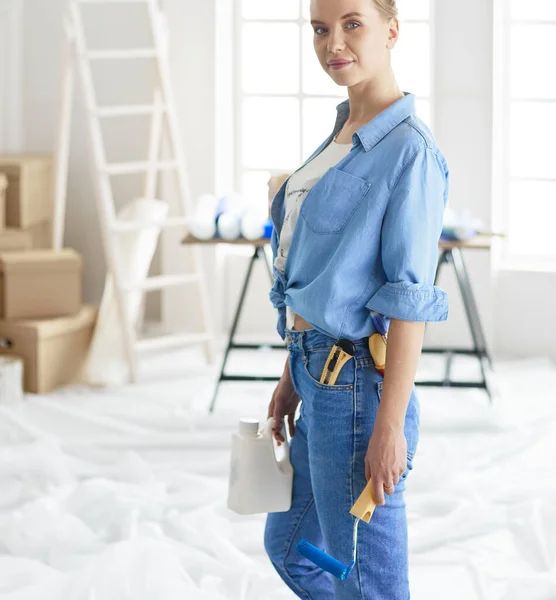 Ganska smilling kvinna målning interiör vägg i hemmet med färg roller — Stockfoto