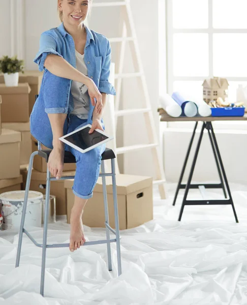 Mujer joven sentada en una silla blanca en una habitación vacía, pensando en algo — Foto de Stock