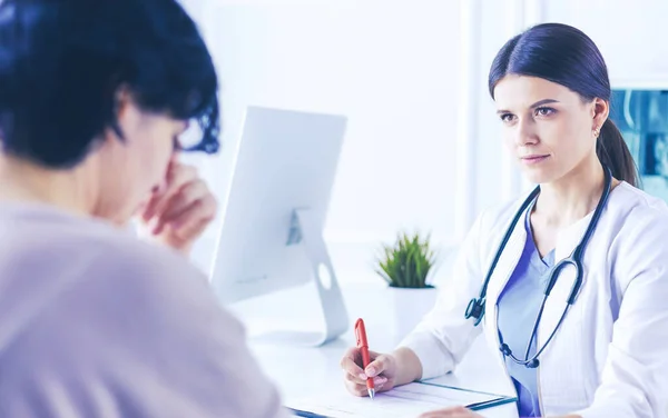 Vrouwelijke dokter kalmeert een patiënt in een ziekenhuis spreekkamer, houdt haar hand vast — Stockfoto