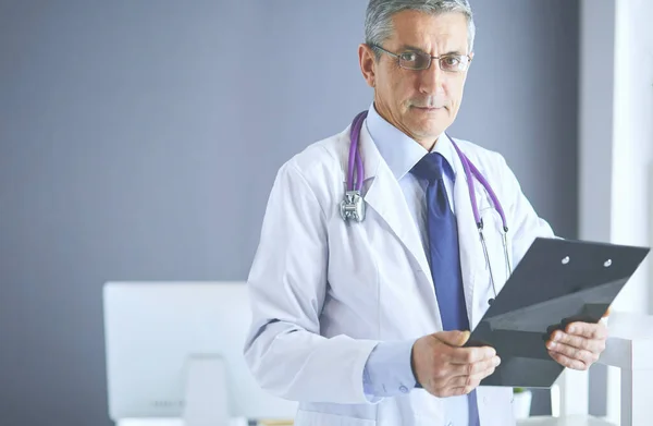 Mężczyzna lekarz pisze notatki na schowku w szpitalu — Zdjęcie stockowe