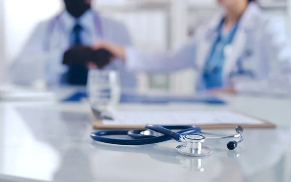 Twee vrolijke glimlachende jonge medische mensen die elkaar de hand schudden op kantoor. Dokters. Teamwork — Stockfoto