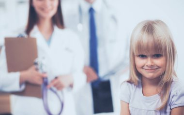 Kadın doktor ameliyatta steteskopla çocuğu muayene ediyor.