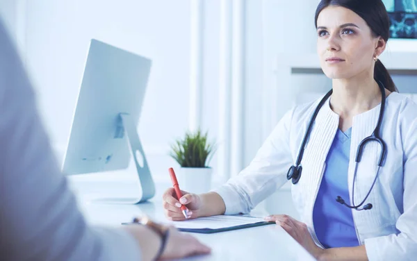 Médico y paciente discutiendo problemas médicos en una sala de consulta del hospital. Doc rellenando un formulario de pacientes — Foto de Stock