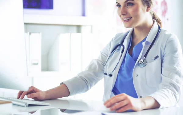 Doctora joven sentada en un escritorio y trabajando en la computadora en la oficina del hospital. Atención médica, seguro y concepto de ayuda. Médico listo para examinar al paciente —  Fotos de Stock