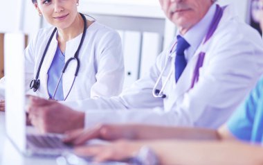 Parlak bir hastane odasında meslektaşlarıyla çalışan gülümseyen bir doktor.