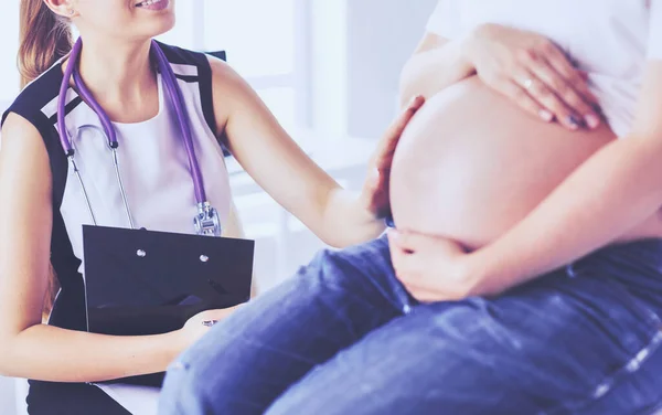 Νεαρή γυναίκα γιατρός που εξετάζει έγκυο γυναίκα στην κλινική. — Φωτογραφία Αρχείου