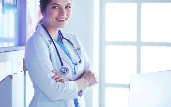 Giovane donna medico in uniforme bianca in piedi in ambulatori ufficio — Foto Stock