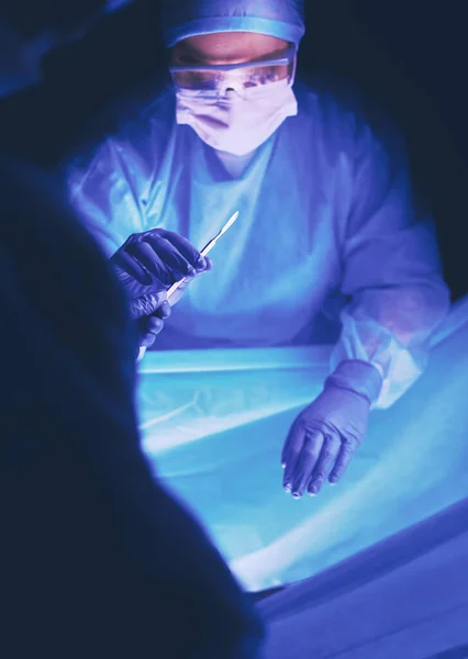 Médecin pratiquant une chirurgie dans un fond sombre. — Photo