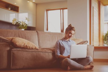oturma odasında yere üstünde laptop ile mutlu bir kadın