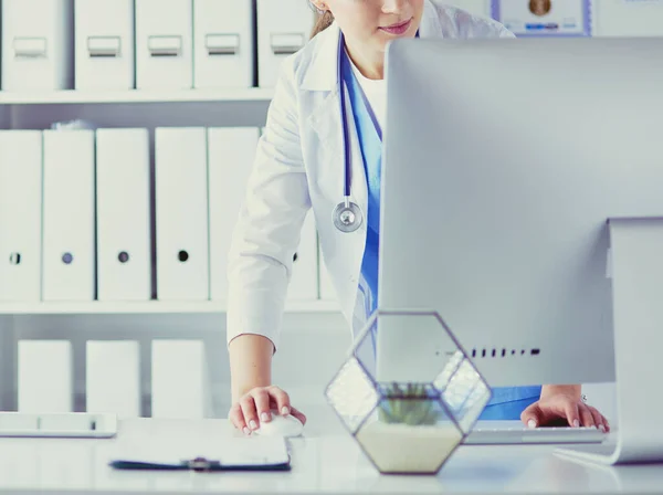 Portrait of female physician using laptop computer while standing near reception desk at clinic or emergency hospital