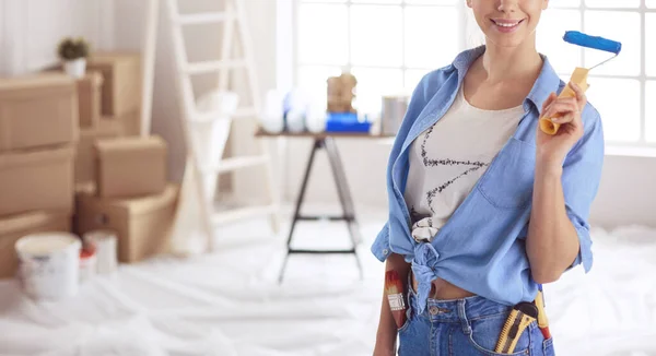 Pretty smilling woman painting interior wall of home with paint roller — Stock Photo, Image