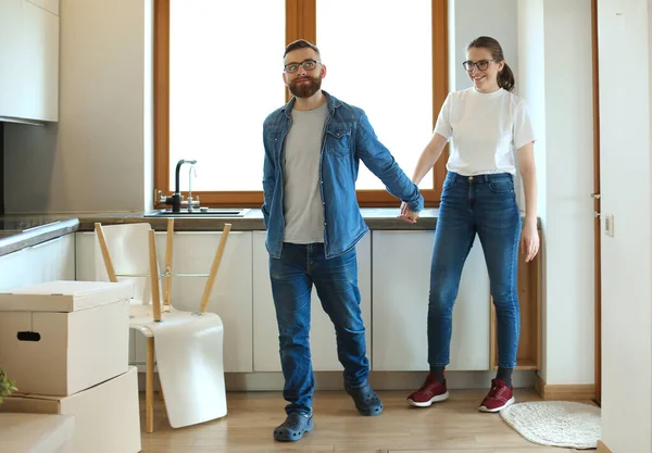 Couple fille et le gars regardant une boîte pour se déplacer tandis que l'homme et la femme debout parmi les boîtes. — Photo