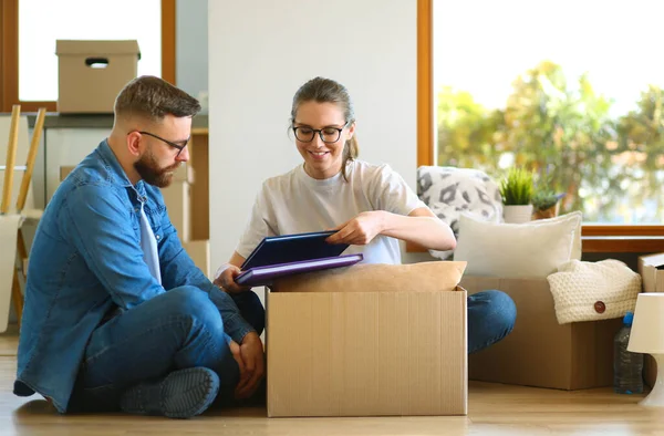 Casal feliz olhando para álbum de fotos ao desempacotar coisas após a mudança para novo apartamento — Fotografia de Stock