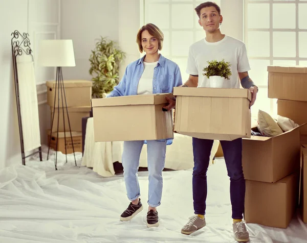 Uma menina e um cara segurando caixas para mover as mãos e olhando dentro da caixa — Fotografia de Stock