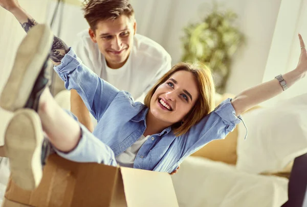 Casal feliz se divertindo e montando em caixas de papelão em nova casa — Fotografia de Stock