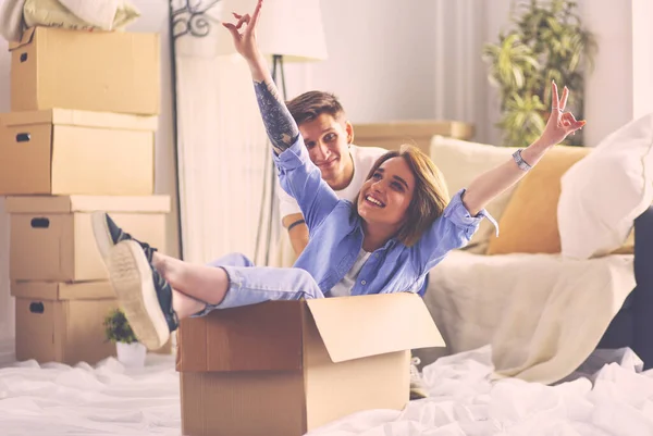 Casal feliz se divertindo e montando em caixas de papelão em nova casa — Fotografia de Stock