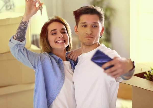 Jeune homme heureux et femme faire selfie sur smartphone, tenant les clés de la nouvelle maison après l'achat appartement de la maison Photo De Stock