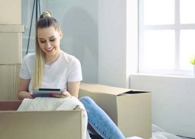 Güzel bekar bir kadın kutuları açıyor ve yeni bir eve taşınıyor. Bir kadın buraya bak tablet