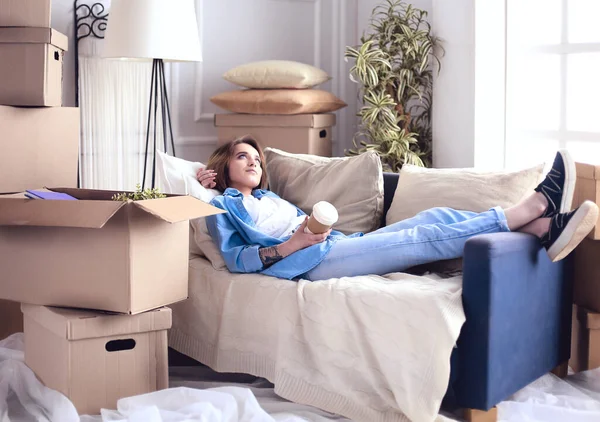 Glimlachende jonge vrouw liggend op de bank in nieuw appartement — Stockfoto