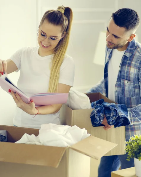 Ein frisch verheiratetes Paar packt Kartons aus und bezieht ein neues Zuhause. Positive Emotionen. — Stockfoto