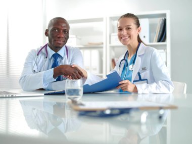 Ofiste tokalaşırken gülümseyen iki genç tıp adamı. Doktorlar. Takım çalışması.