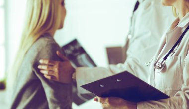 Doktor ve hasta tarama sonuçlarını tarama merkezinde tartışıyor