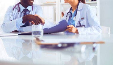Ofiste tokalaşırken gülümseyen iki genç doktor.