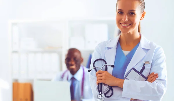 Eine lächelnde Ärztin mit einem Ordner in Uniform drinnen — Stockfoto