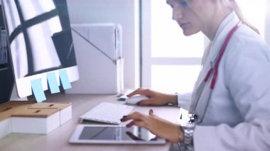 Kadın doktor dijital tablet kullanıyor ve tıbbi ofiste size gülümsüyor.