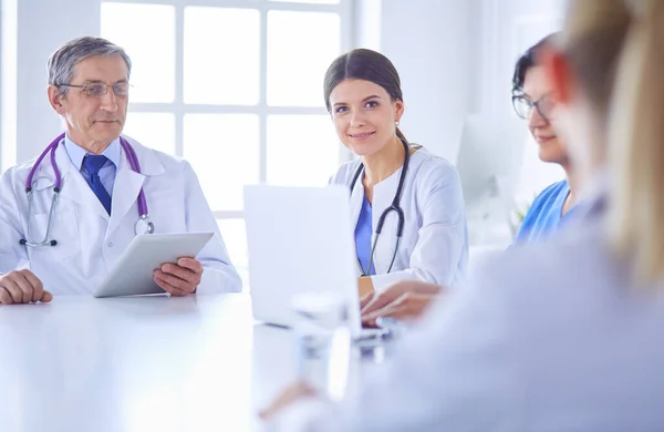 Equipo médico serio discutiendo casos de pacientes en un consultorio luminoso — Foto de Stock