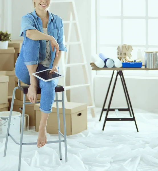 Mujer joven sentada en casa y comprando muebles nuevos a través de Internet usando una tableta — Foto de Stock