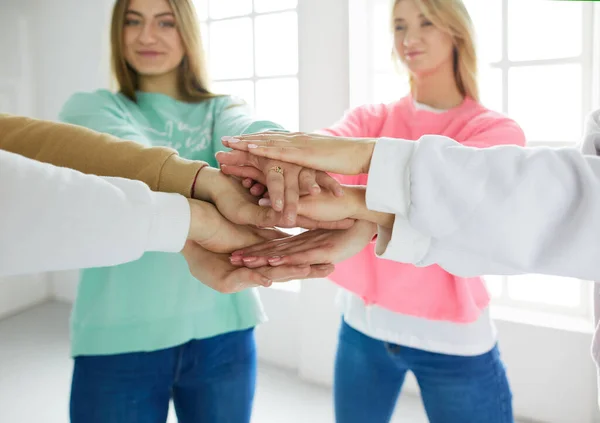People joining hands, young women standing together
