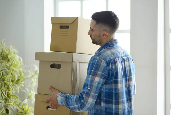 A moving man sitting on the floor in empty apartment, Among the Boxes, Checking the List of Things