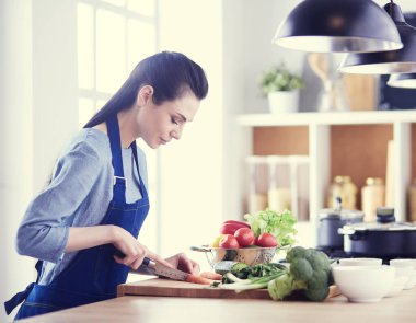 Mutfakta sebze doğrayan genç bir kadın.