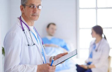 Doktor bir hastanın ve doktorun önünde klasörü tutuyor.