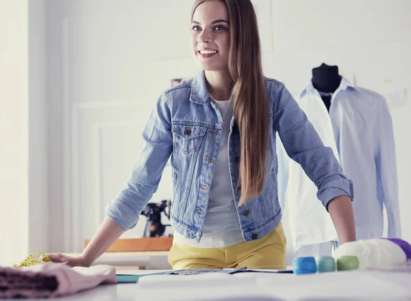 Hermoso diseñador de moda de pie cerca del escritorio en el estudio — Foto de Stock